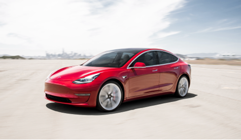 A red Tesla Model 3 is parked on a deserted airport runway on a bright cloudy day